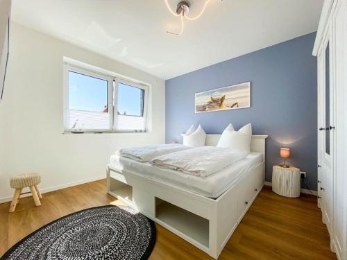 1 dormitorio con cama blanca y pared azul en Meerestraum, en Grömitz