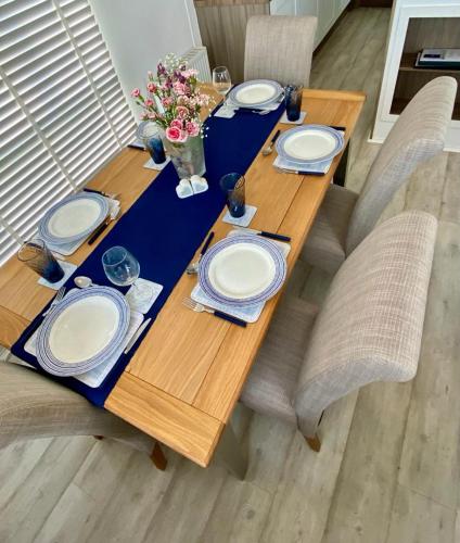 a wooden table with plates and flowers on it at Loxley's Devon Lodge in Brixham