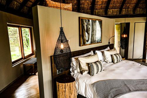 ein Schlafzimmer mit einem Bett in einem Zimmer mit Fenstern in der Unterkunft Laluka Safari Lodge - Welgevonden Game Reserve in Welgevonden Game Reserve