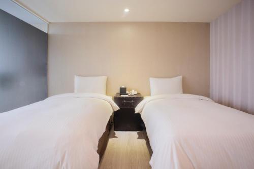 two beds sitting next to each other in a room at XinsheHotel - Chungli in Zhongli