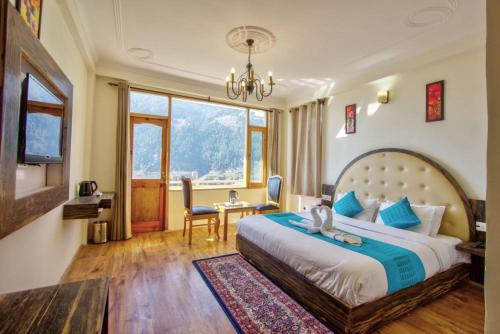 1 dormitorio con 1 cama grande, mesa y sillas en HOTEL WILD ROSE, en Jagatsukh