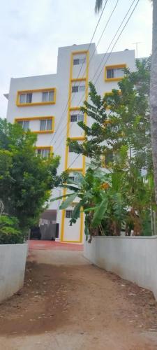 un edificio blanco y amarillo con árboles delante en Nachiyar Suites en Thiruvananthapuram