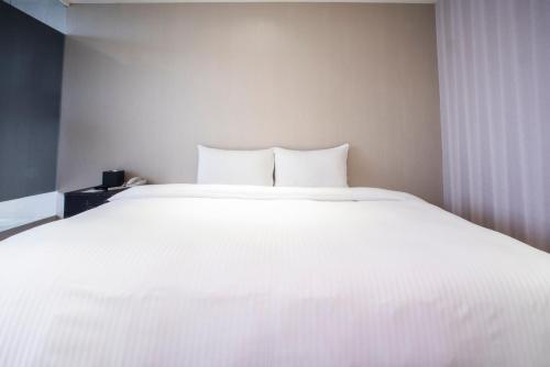 a large white bed in a room with a window at XinsheHotel - Chungli in Zhongli