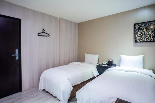 two beds in a hotel room with white sheets at XinsheHotel - Chungli in Zhongli