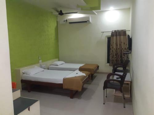 a room with three beds and a chair in it at Hotel Uma Executive Lodging in Nānded