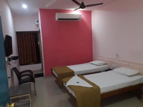 a room with two beds and a red wall at Hotel Uma Executive Lodging in Nānded