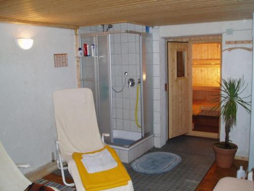 a bathroom with a shower and a chair in a room at Haus Meinecke in Bad Hindelang