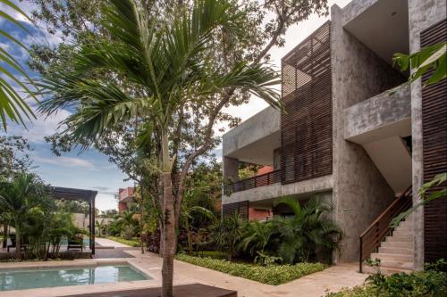 a palm tree in front of a building with a swimming pool at Panacea Condo Tulum in Tulum