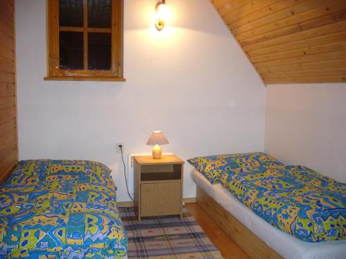 a bedroom with two beds and a table with a lamp at Chata Ala in Demanovska Dolina