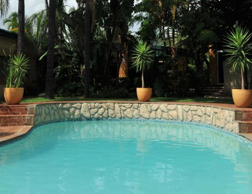 a swimming pool with a stone wall and plants at Safari Hotel & Convention Centre in Rustenburg