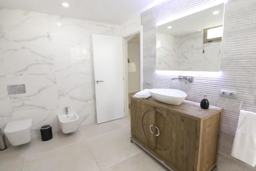 a white bathroom with a sink and a toilet at Villa Ozeano in Costa Calma