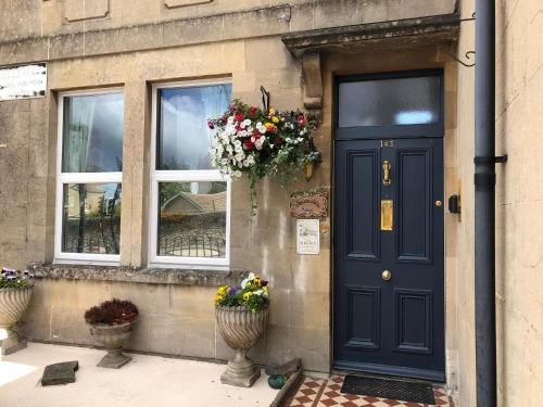 una porta blu con fiori sul lato di un edificio di Devonshire House a Bath