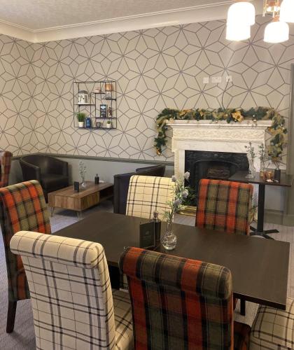 a dining room with a table and a fireplace at Green Hotel in Kinross