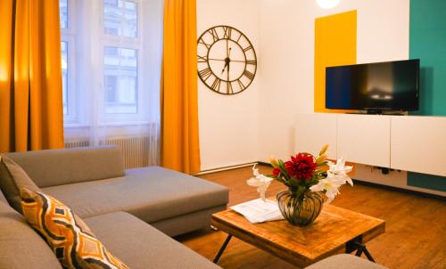 維也納的住宿－Modern Apartment Wiener Stadthalle，客厅配有沙发和带时钟的桌子