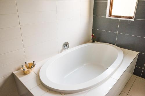 a large white bath tub in a bathroom at Tamboti Guest Lodge in Pretoria