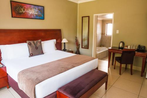 a bedroom with a large bed and a bathroom at Tamboti Guest Lodge in Pretoria