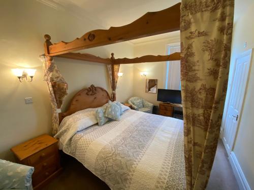 a bedroom with a large bed with a wooden canopy at The Old Manse Pickering in Pickering