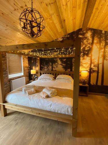 um quarto com uma cama grande e luzes de Natal em Roe Lodge at Owlet Hideaway - with Hot Tub, Near York em Seaton Ross