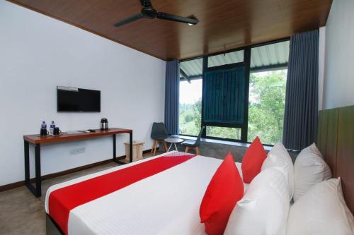 um quarto com uma cama grande e almofadas vermelhas e brancas em The Domain em Piliyandala