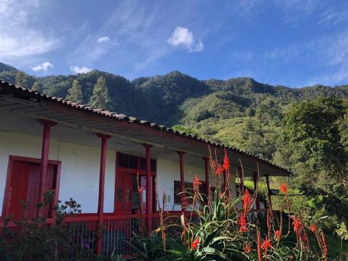 uma casa com acabamento vermelho em frente a uma montanha em Birdglamping Los Arboles Hotel em Salento