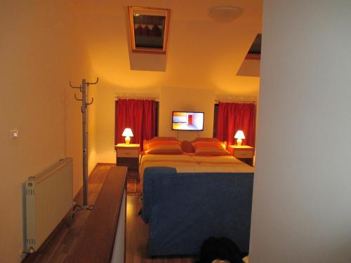 1 dormitorio con 1 cama con almohadas de color naranja y TV en Studio Brnat en Kobarid
