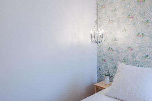 una camera da letto con lampadario pendente e parete bianca di Casas de Mar - Casa Estrela do Mar a Olhão