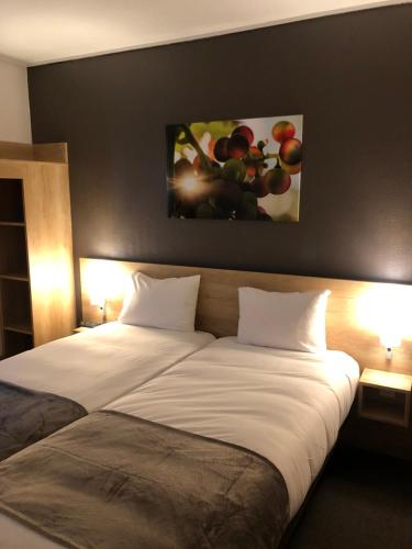 a large bed in a hotel room with two lamps at Hotel Wood Inn Bordeaux Aéroport in Mérignac