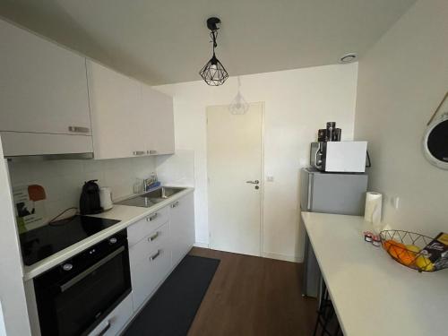 a kitchen with white cabinets and a sink and a refrigerator at T1 bis 35 m2 lit queen size tout équipé in Pau