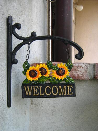 a welcome sign hanging on a wall with sunflowers at B&B Casa Dolce Casa in Candelo