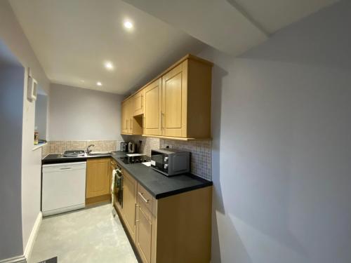 a small kitchen with wooden cabinets and a microwave at The Hidden Nook in Whitby