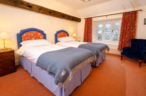 a bedroom with two beds and a blue chair at Swallows House in Elterwater