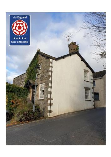 a white building with a sign on the side of it at Valentine Cottage in Ambleside