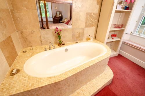 eine Badewanne im Bad mit Spiegel in der Unterkunft Valentine Cottage in Ambleside
