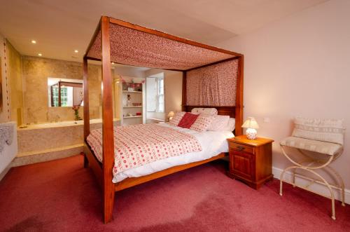 ein Schlafzimmer mit einem Himmelbett und einer Badewanne in der Unterkunft Valentine Cottage in Ambleside