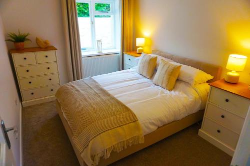 a bedroom with a bed with two night stands and a window at Staycation at Pine Cottage, a newly refurbished holiday cottage in Goodwick