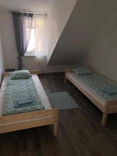 two beds in a room with a window at Good times apartmán in Žilina