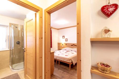 Habitación con cama y puerta de cristal que conduce a un dormitorio. en Majon Viva en Campitello di Fassa