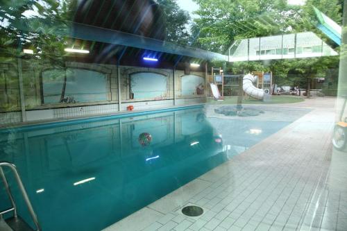 a large swimming pool with a slide in a building at Vakantiebungalow De Schaapskooi in Epe