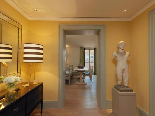 a living room with a statue on a pedestal at Rocco Forte Hotel De Russie in Rome