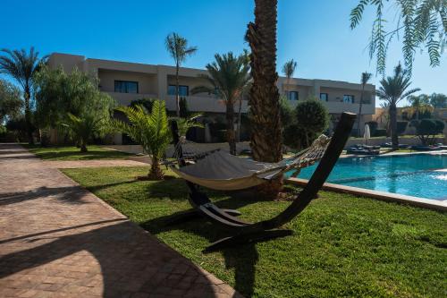 a hammock sitting on the grass next to a pool at Sirayane Boutique Hotel & Spa Marrakech in Marrakesh