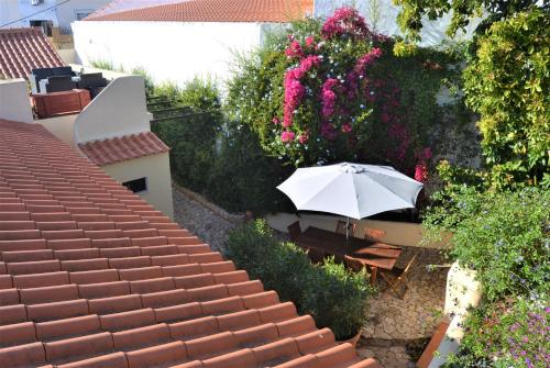an umbrella sitting on top of a roof with flowers at Garden in the City in Silves