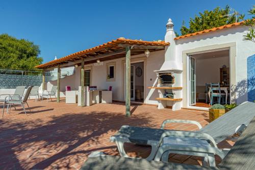 a patio with a table and chairs and a fireplace at Casa Mimao in Albufeira