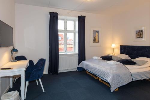 a bedroom with a bed and a desk and a table at Skagen Hotel in Skagen