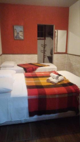 a bedroom with two beds with a plaid blanket at Pousada Horto dos Contos in Ouro Preto