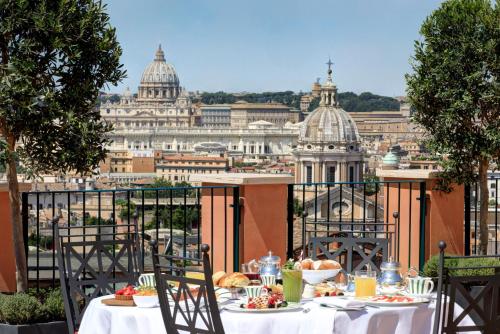 a table with food on a balcony with a view of the city at Rocco Forte Hotel De La Ville in Rome