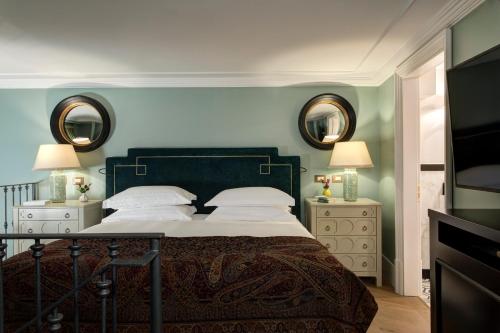 a bedroom with a bed with two night stands and two mirrors at Rocco Forte Hotel De La Ville in Rome