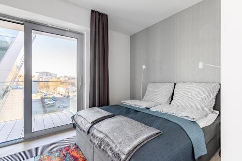 a bedroom with a bed and a large window at Stan Apartamenty Yacht Park Gdynia in Gdynia