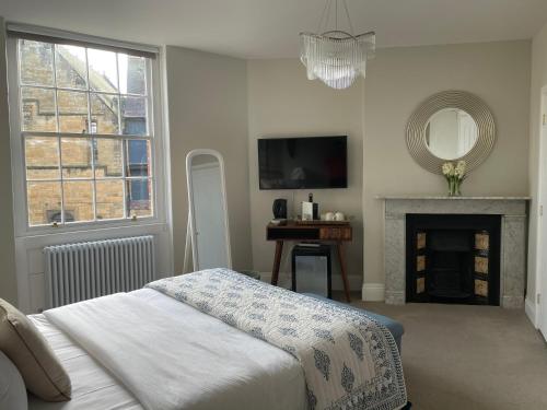 a bedroom with a bed and a fireplace and a mirror at The Cross Keys Sherborne in Sherborne