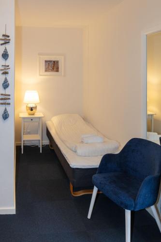 a bedroom with a bed and a blue chair at Skagen Hotel in Skagen