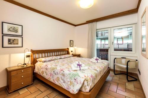 a bedroom with a bed and a chair and a window at Valle Maura in Canazei